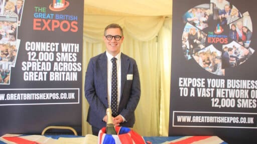 A photograph of ALec Jones-Hall between two vertical pop-up banners promoting Great British Expos