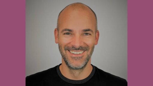 Portrait of Gary Arnold, Managing Partner (Advisory & Consulting) at Salocin Group. He is smiling, wearing a black shirt, with a light grey background and mauve borders on either side.