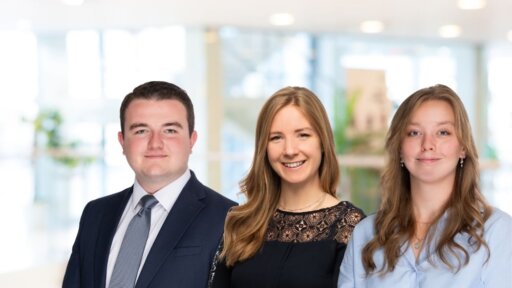 Group portrait of Goughs Solicitors' trainees, pictured left to right: Samuel Berkeley in a navy suit and tie, Eden Wey in a black lace-detailed top, and Adelaide Longhurst in a light blue blouse, standing together in a bright office setting.