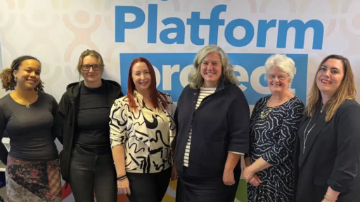 Group photo of six individuals standing in front of a wall with ‘The Platform Project’ branding. From left to right: Taya Boothe and Riley Mathers (Youth Trainers on the Engage programme), Sadie Sharp, Heidi Alexander, Carole Kitching and Sara Witham. The background features colourful abstract human figures.