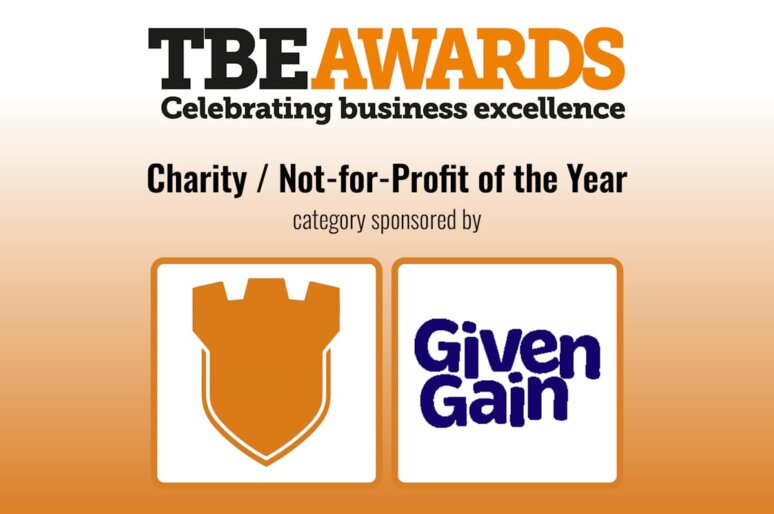 TBE Awards logo with tagline ‘Celebrating business excellence’. Below, text reads ‘Charity / Not-for-Profit of the Year – category sponsored by’. Two sponsor logos are shown: an orange shield icon on the left and the GivenGain logo in blue on the right, all on a gradient orange background.