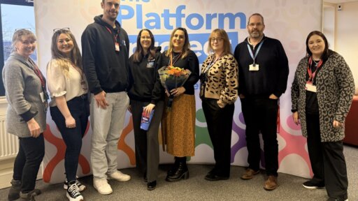 A group of eight people standing together in front of a backdrop displaying “The Platform Project.” From left to right: Amanda Hancock, Laurie Kyle, Richard Macarthur, Giselle Grace, Sara Witham, Hannah Thandi, Ben Vickery, Kate Colman