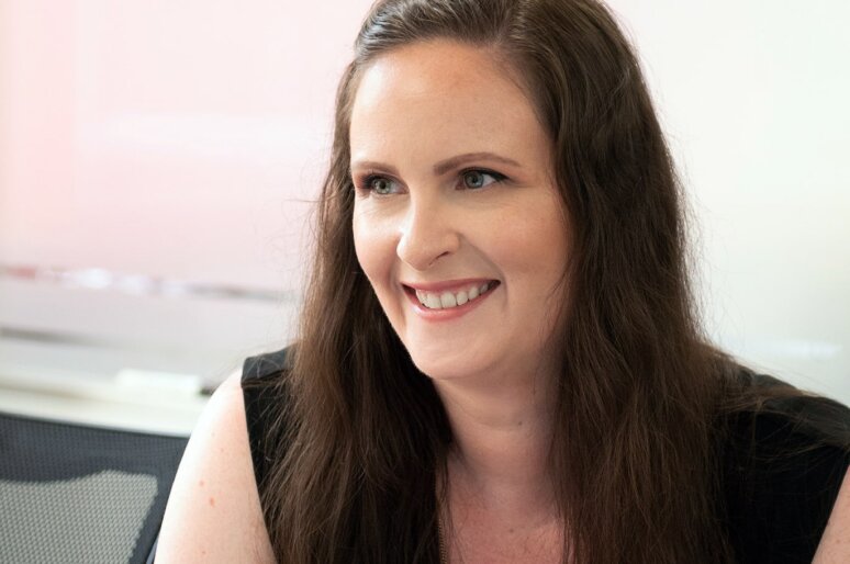 a headshot of the HR Dept's Helen Imbusi. She has brown hair, is smiling and looking away from the camera