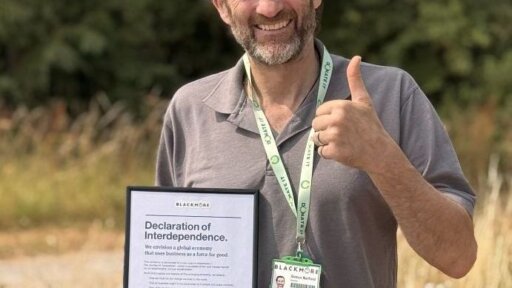 Simon Barfoot, Founder of Blackmore UK standing outdoors on grass, wearing a grey polo shirt and a green lanyard with a BLACKMORE ID badge