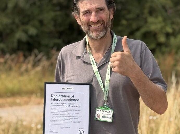 Simon Barfoot, Founder of Blackmore UK standing outdoors on grass, wearing a grey polo shirt and a green lanyard with a BLACKMORE ID badge