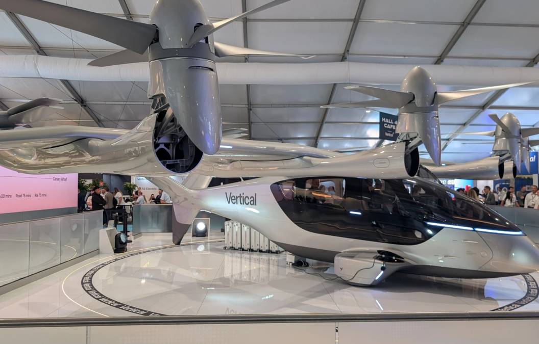 A sleek silver electric VTOL aircraft from Vertical Aerospace displayed inside an exhibition hall