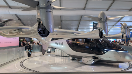 A sleek silver electric VTOL aircraft from Vertical Aerospace displayed inside an exhibition hall